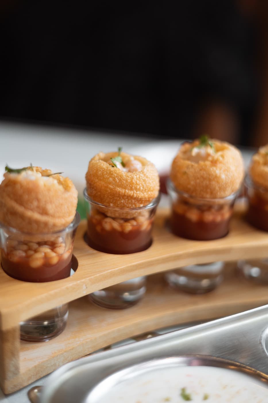 Pani puri shots served on a wooden board at Jewel of India, a classic Indian street food appetizer